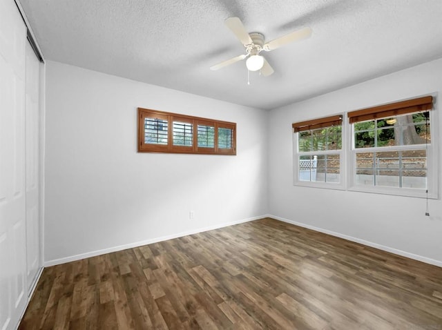 empty room featuring ceiling fan, dark wood-type flooring, and a textured ceiling