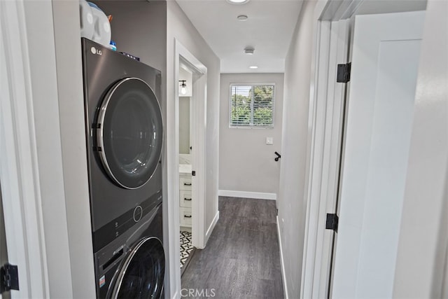 washroom featuring stacked washer / dryer and dark hardwood / wood-style flooring