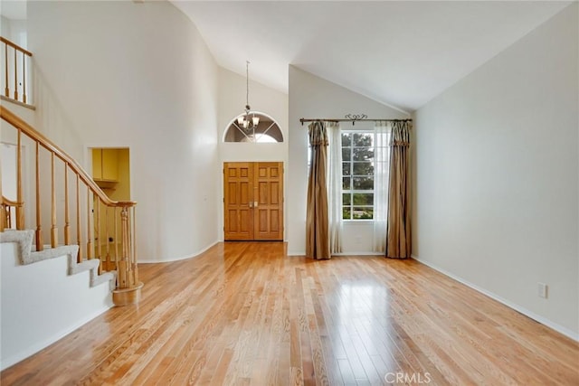 entryway with high vaulted ceiling, a chandelier, and light wood-type flooring