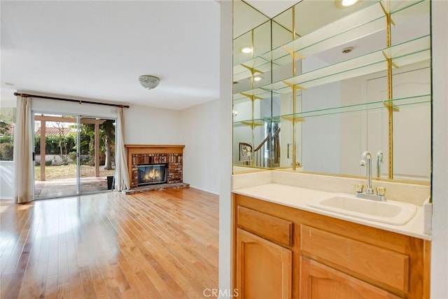 bar featuring a fireplace, light hardwood / wood-style flooring, and sink