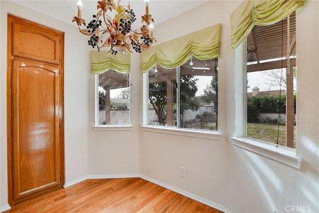 unfurnished dining area featuring light wood-type flooring, an inviting chandelier, and plenty of natural light