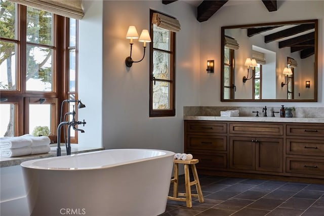 bathroom featuring tile patterned floors, plenty of natural light, beamed ceiling, and a tub to relax in