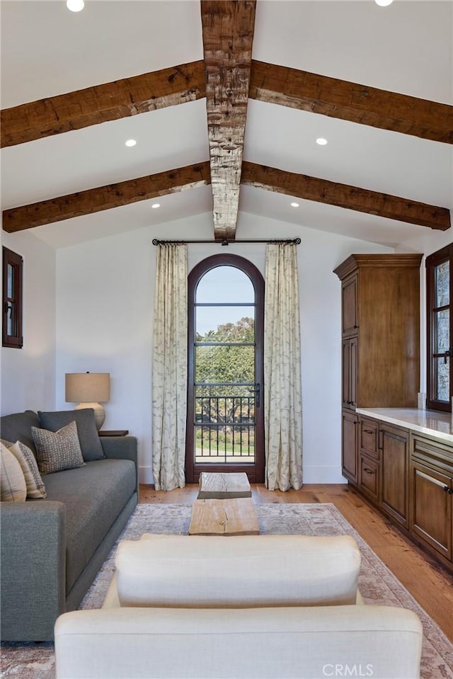 living room with vaulted ceiling with beams and light wood-type flooring