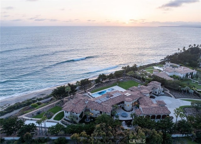 aerial view at dusk with a view of the beach and a water view