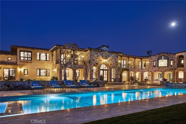 pool at twilight featuring a patio area