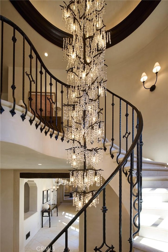 stairs featuring a notable chandelier and a towering ceiling