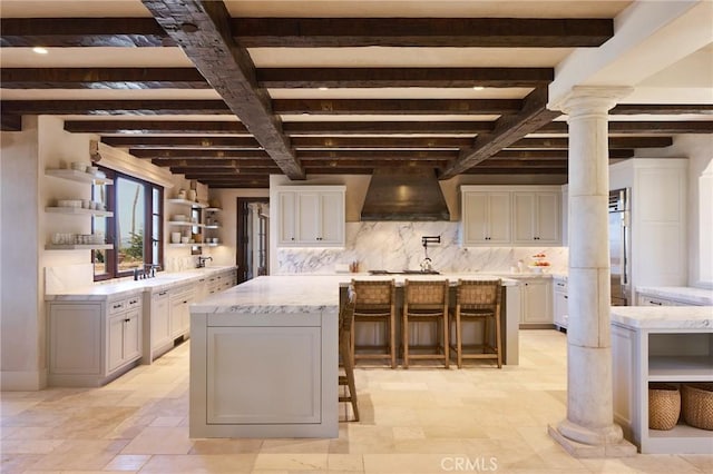 kitchen featuring beamed ceiling, a center island, a breakfast bar area, and custom exhaust hood