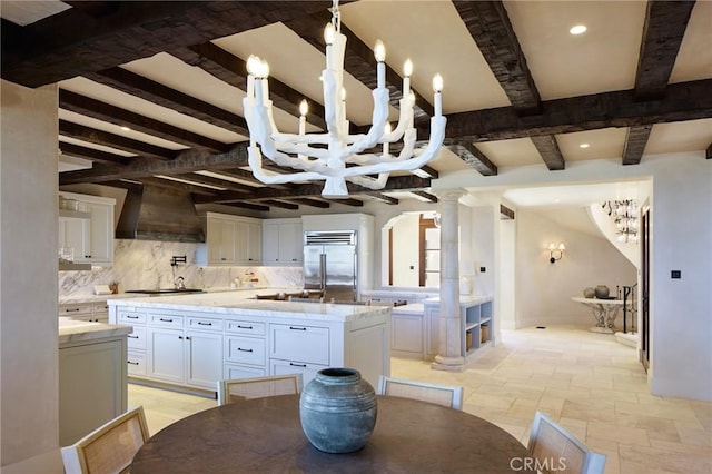 kitchen with custom exhaust hood, white cabinets, decorative backsplash, an island with sink, and appliances with stainless steel finishes