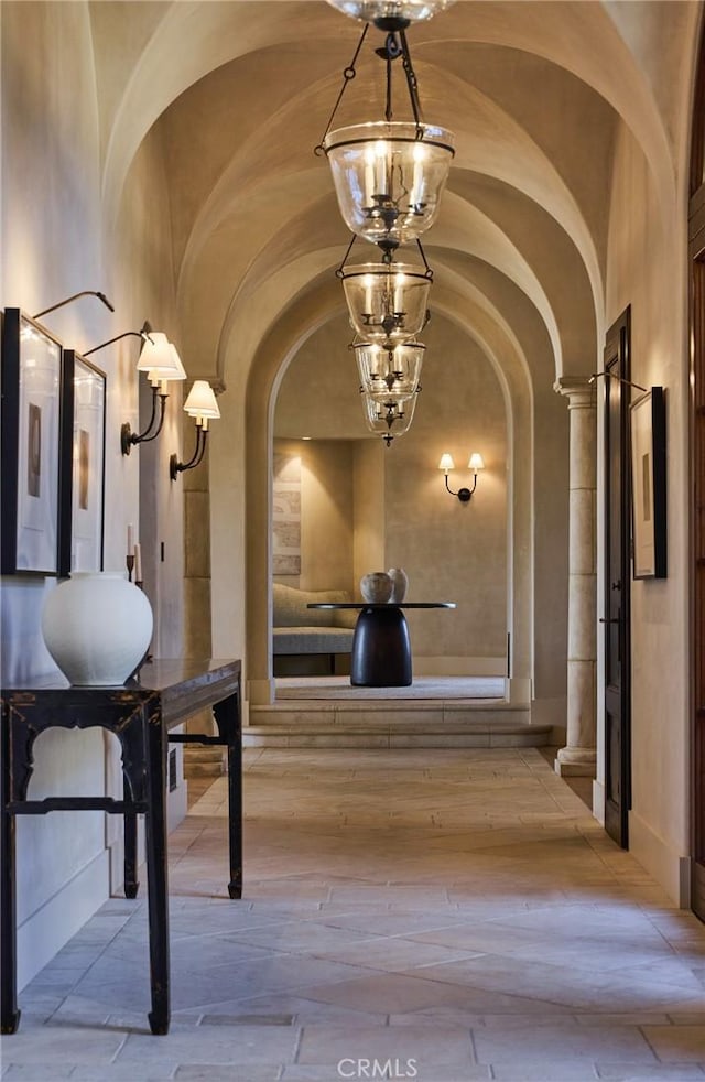 hall with a notable chandelier and vaulted ceiling