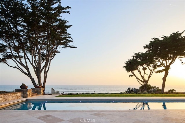 pool at dusk featuring a water view