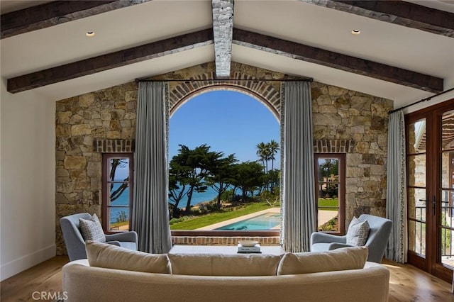 interior space with vaulted ceiling with beams, a healthy amount of sunlight, and light hardwood / wood-style flooring