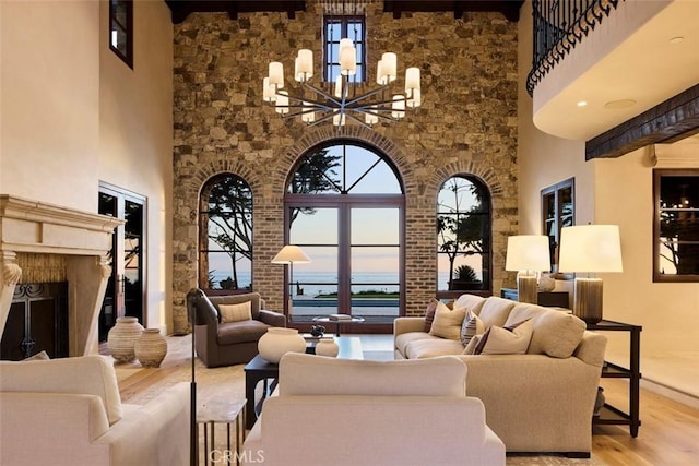 living room featuring a chandelier, a towering ceiling, and light hardwood / wood-style flooring