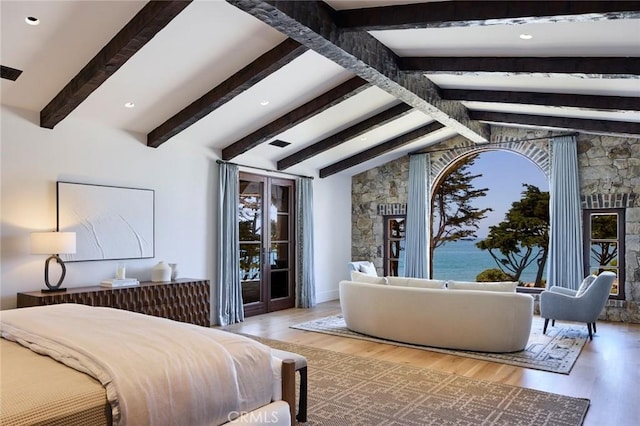 bedroom featuring vaulted ceiling with beams, a water view, and hardwood / wood-style flooring