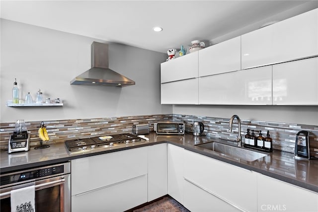 kitchen with stainless steel appliances, tasteful backsplash, wall chimney exhaust hood, and sink