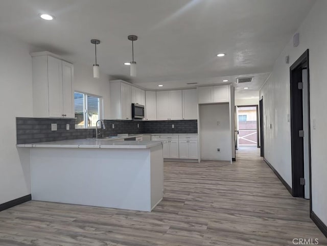 kitchen featuring kitchen peninsula, light hardwood / wood-style flooring, and white cabinetry