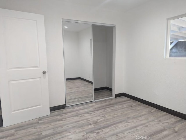 unfurnished bedroom featuring light hardwood / wood-style flooring and a closet