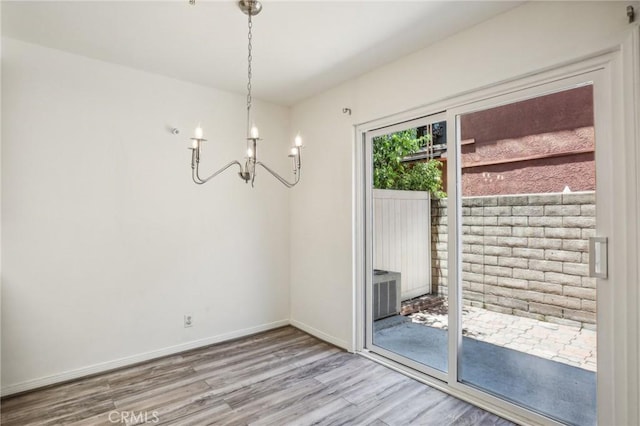 unfurnished dining area featuring an inviting chandelier and hardwood / wood-style flooring