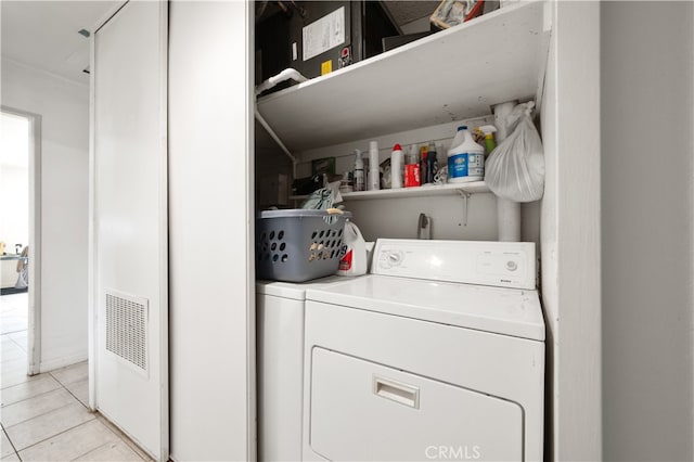 clothes washing area with washing machine and dryer and light tile patterned floors