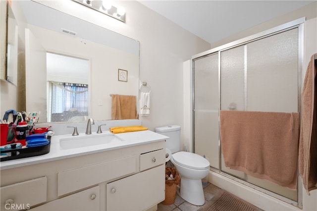 bathroom featuring tile patterned flooring, vanity, toilet, and walk in shower