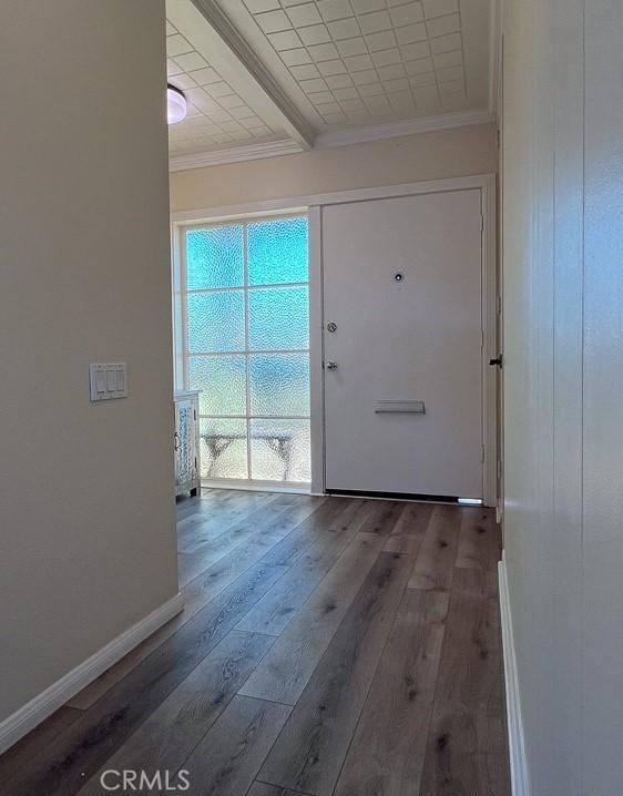 doorway featuring crown molding, baseboards, and wood finished floors