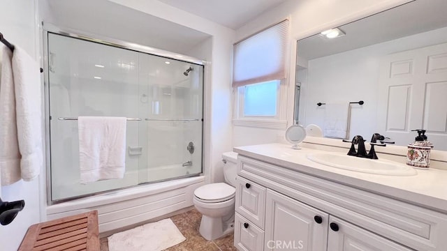 full bath featuring vanity, toilet, and bath / shower combo with glass door