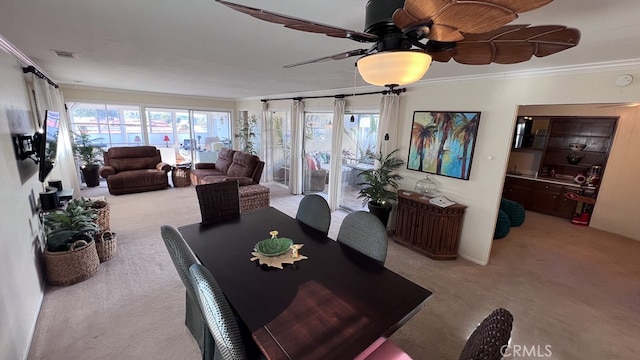 carpeted dining room with visible vents, ceiling fan, and ornamental molding