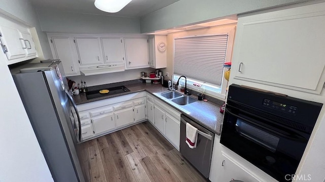 kitchen with light wood-style flooring, a sink, black appliances, white cabinetry, and dark countertops