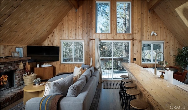 living room with wood walls, dark hardwood / wood-style floors, high vaulted ceiling, and a fireplace