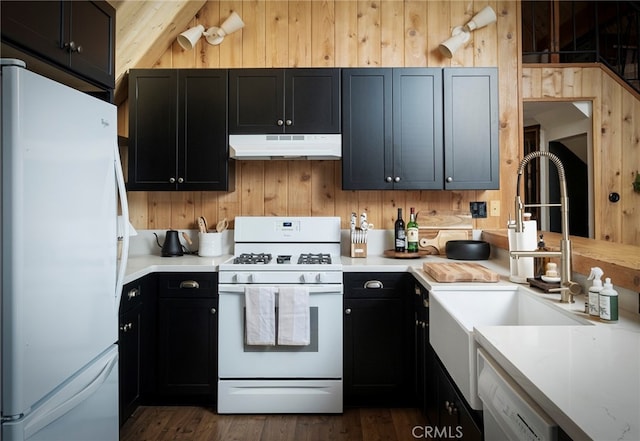 kitchen featuring sink, dark hardwood / wood-style floors, white appliances, and wood walls