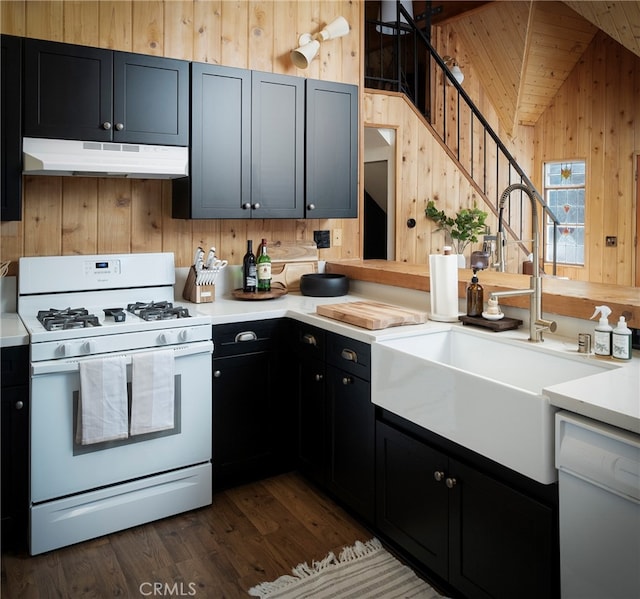 kitchen featuring high vaulted ceiling, wood walls, dark hardwood / wood-style floors, sink, and white appliances