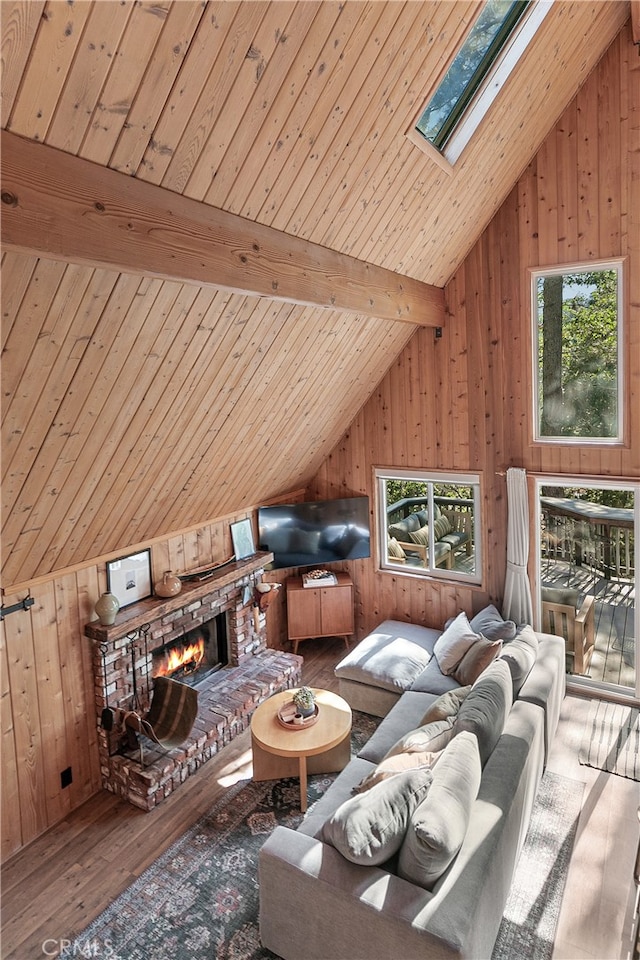 bonus room featuring hardwood / wood-style flooring, wood walls, beamed ceiling, a fireplace, and a skylight