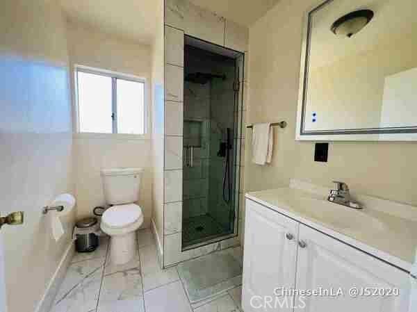 bathroom with vanity, a shower with shower door, tile patterned floors, and toilet