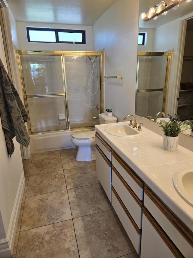 full bathroom with vanity, tile patterned floors, bath / shower combo with glass door, toilet, and a textured ceiling