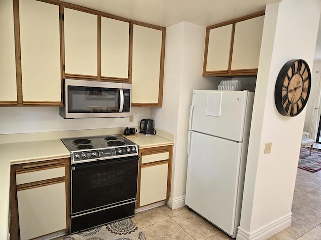 kitchen featuring white cabinets, electric range, white fridge, and light tile patterned flooring