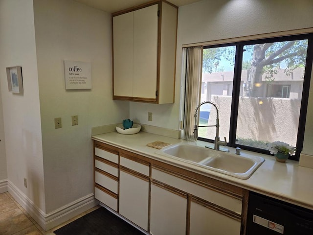 kitchen featuring dishwasher, white cabinets, light tile patterned flooring, and sink