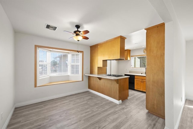 kitchen with kitchen peninsula, a kitchen breakfast bar, gas cooktop, ceiling fan, and light hardwood / wood-style flooring