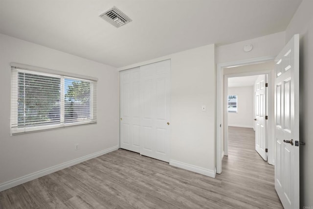 unfurnished bedroom featuring light wood-type flooring and a closet