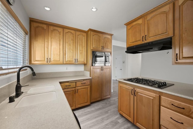 kitchen with gas stovetop, light hardwood / wood-style flooring, stainless steel microwave, and sink