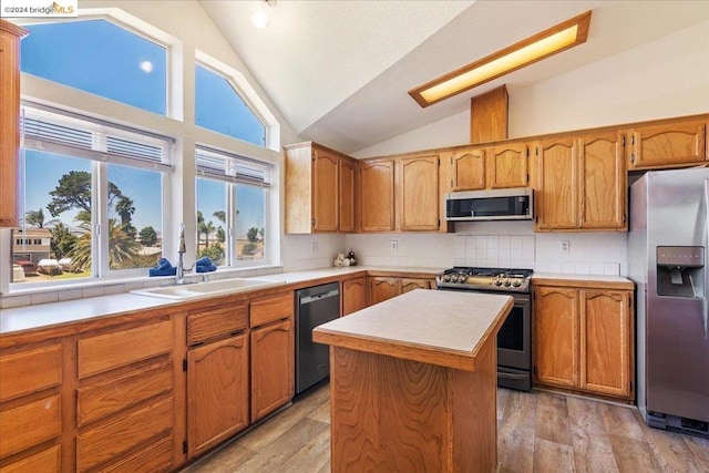 kitchen featuring light hardwood / wood-style floors, vaulted ceiling, stainless steel appliances, a center island, and sink