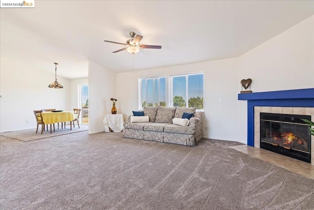 living room with a tile fireplace, carpet, and ceiling fan