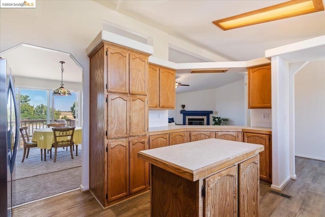 kitchen with pendant lighting, kitchen peninsula, ceiling fan, and dark hardwood / wood-style floors