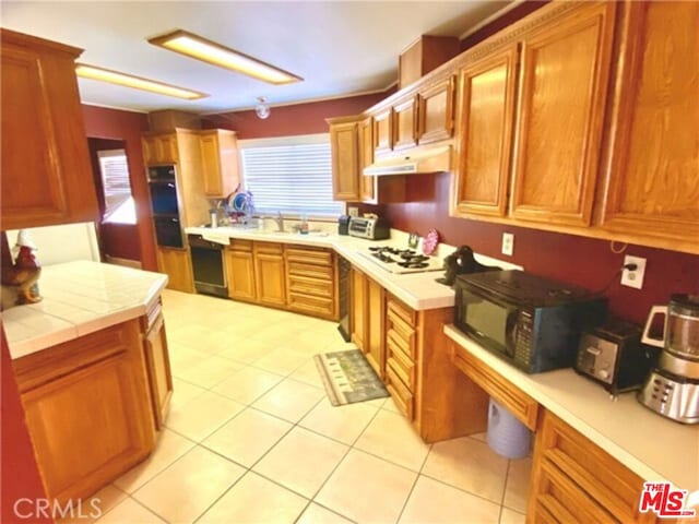 kitchen featuring white gas stovetop, sink, light tile patterned floors, and tile counters