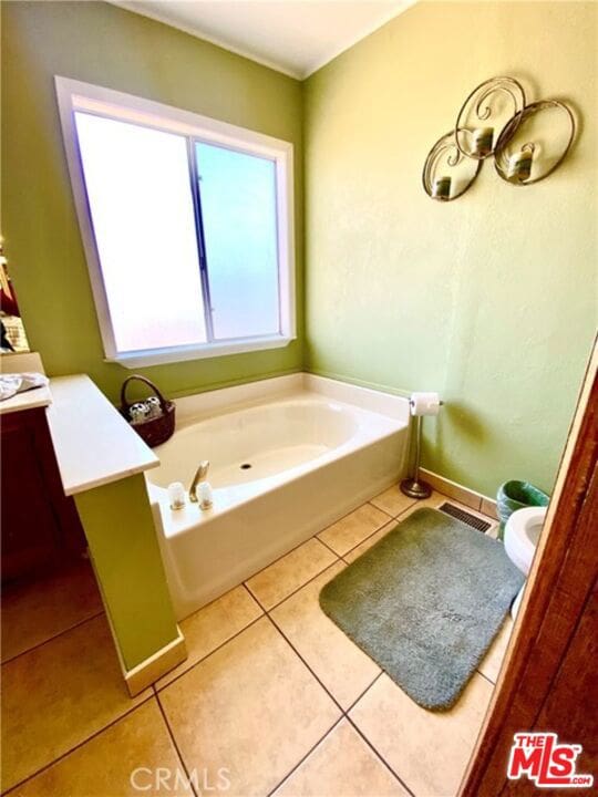 bathroom with tile patterned flooring, vanity, and a tub to relax in