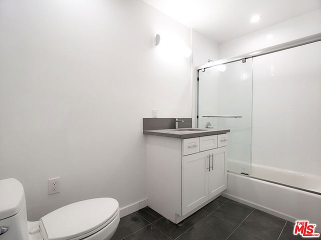 full bathroom with combined bath / shower with glass door, tile patterned floors, vanity, and toilet