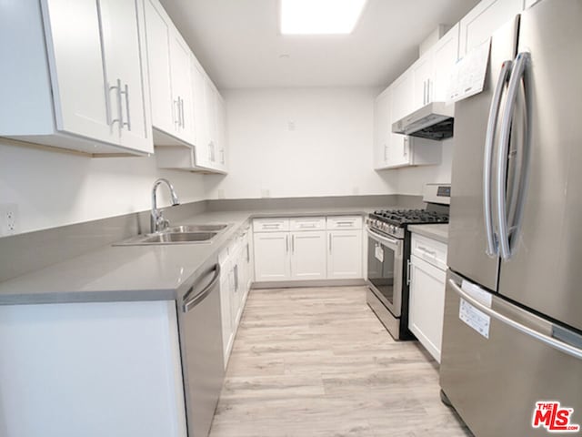 kitchen featuring appliances with stainless steel finishes, light wood-type flooring, white cabinetry, and sink