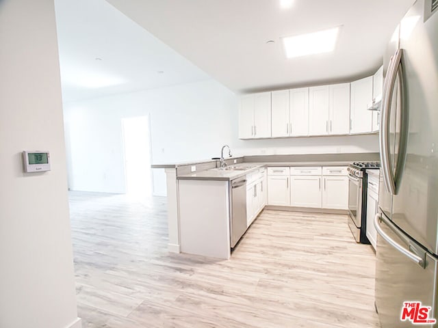 kitchen featuring kitchen peninsula, appliances with stainless steel finishes, sink, white cabinets, and light hardwood / wood-style floors