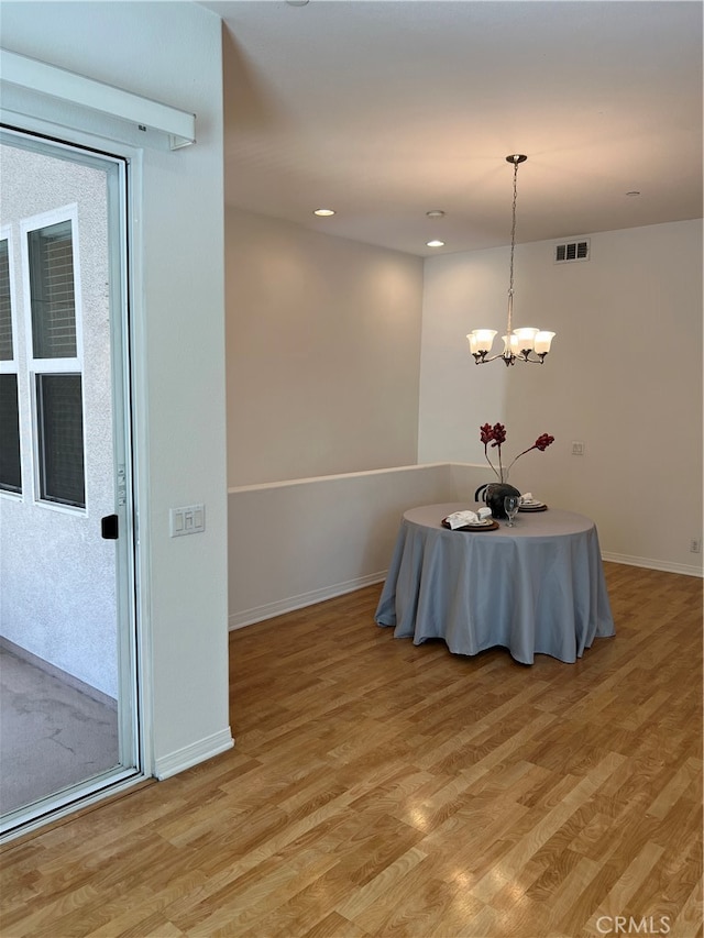 unfurnished dining area with light wood-type flooring and a notable chandelier