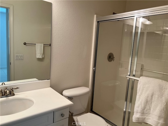 bathroom featuring vanity, a shower with shower door, and toilet