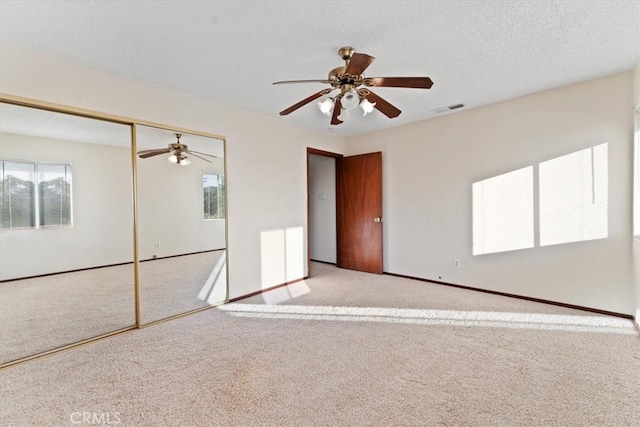 carpeted empty room featuring a textured ceiling and ceiling fan