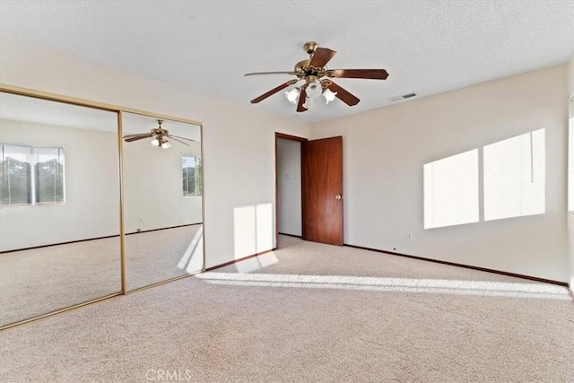 unfurnished bedroom with a closet, baseboards, carpet flooring, visible vents, and ceiling fan